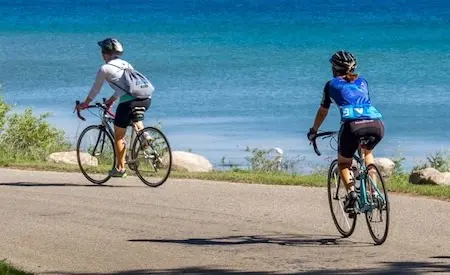 Cyclists riding on the Burt Lake Trail along the North side of Burt Lake in Northern Michigan.