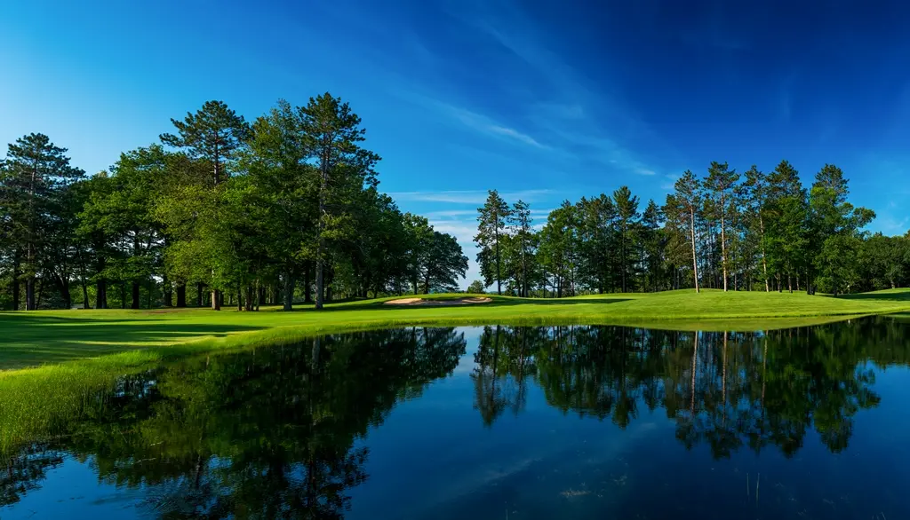 A picturesque view of Indian River Golf Club with towering pines over a water feature.