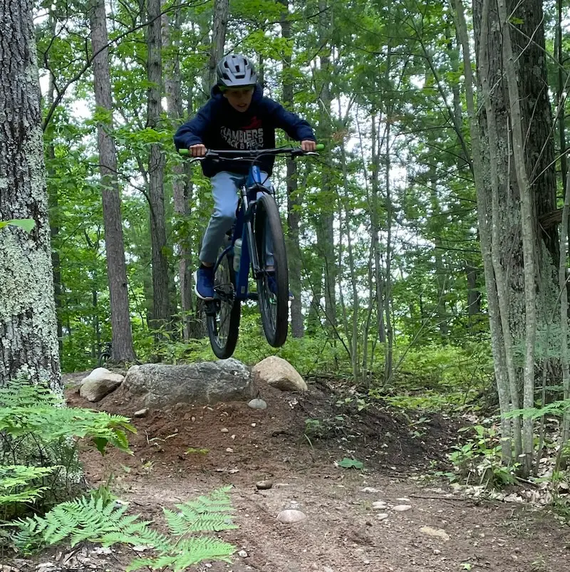 A child riding a mountain bike and wearing a helmet rides through the Melvin Family Hiking and Biking Trails in Topinabee, Michigan.