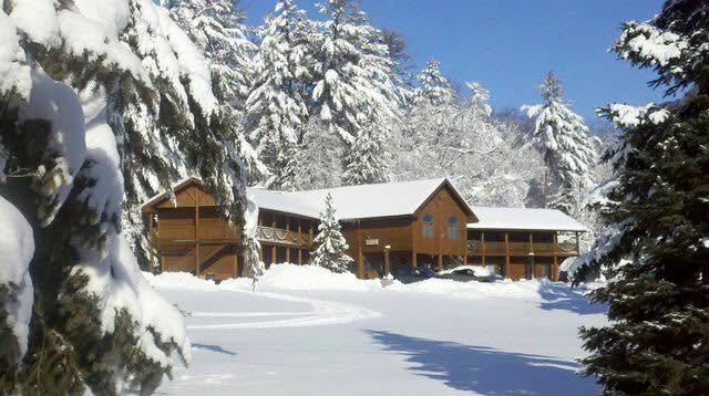 The Northwoods Lodge in Indian River, Michigan covered in snow and flanked by towering pines.