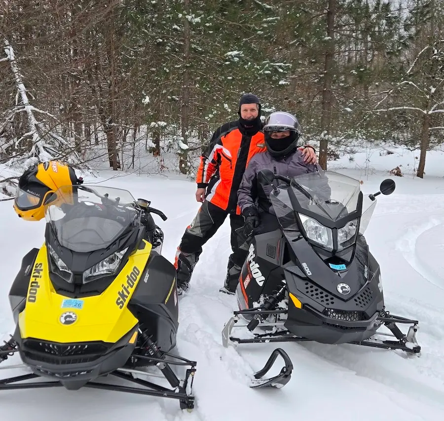 Snowmobilers riding through Northern Michigan's snow-covered forests.